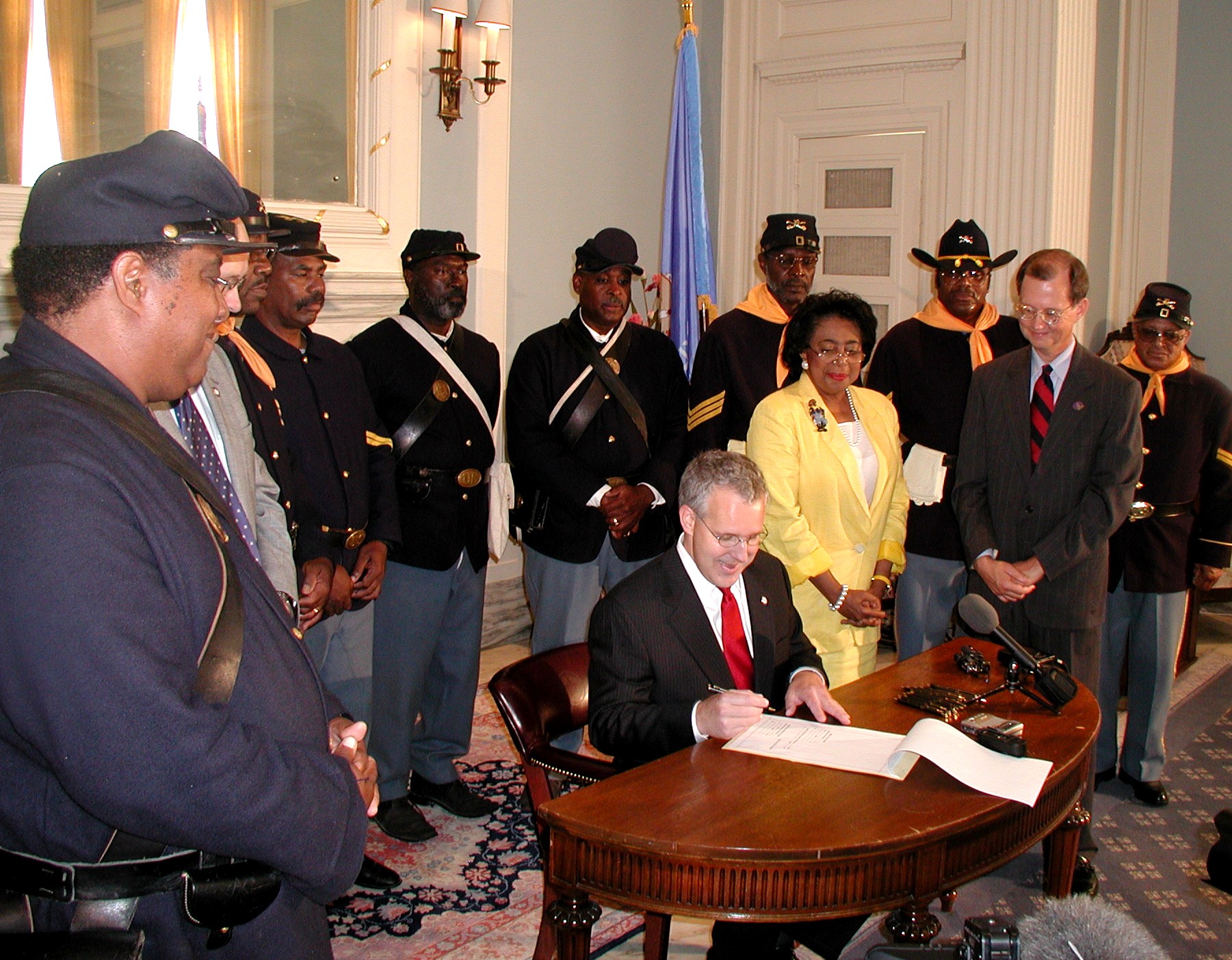 Sen. Eason McIntyre and the Buffalo Soldiers watch Gov. Henry sign the bill.