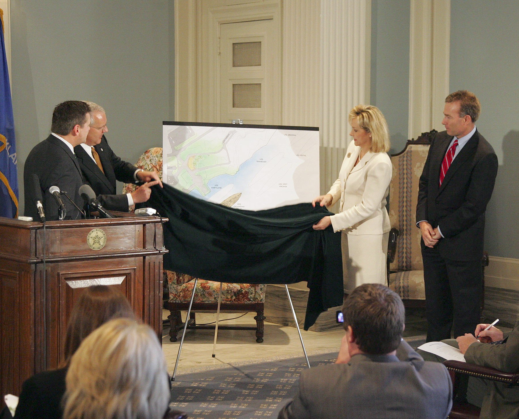 Arcitect Don Beck and Sen. Jim Reynolds look on as Gov. Henry and Lt. Gov. Fallin unveil initial memorial plans.