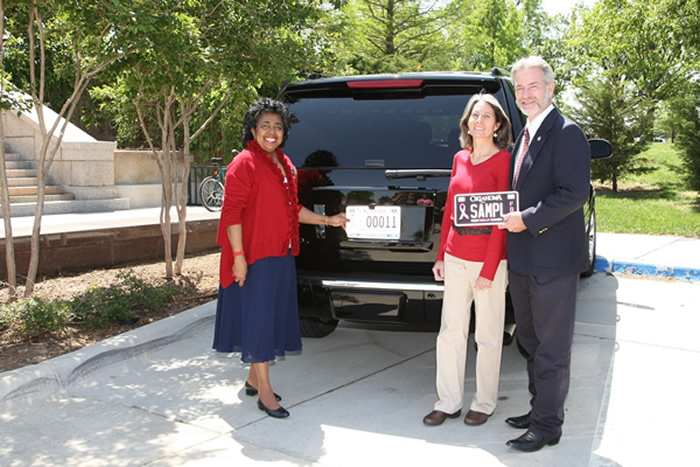 Sen. Judy Eason McIntyre (D-Tulsa) and Rep. Tommy Hardin (R-Madill), along with his wife Carol who is a 9 year breast cancer survivor, display the two new designs of the “Fight Breast Cancer” license plates. 