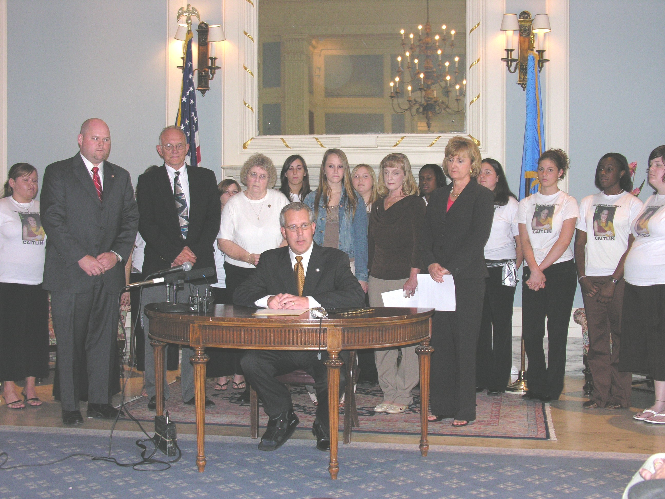 Governor Brad Henry signs the Caitlin Wooten Act into law Tuesday while Sen. Susan Paddack, Rep. Wes Hilliard and family members look on. 